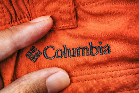 Tambov, Russian Federation - September 27, 2017 Embroidered Logo Columbia On Red Clothes Between Person Fingers.