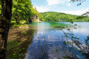 Cascades of pure fresh water rushing down brown, mossy rocks into an azure colored lake at the Plitvice Lakes National Park, Plitvička Jezera, Croatia