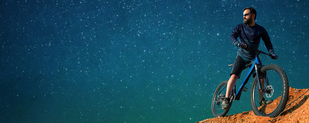 Conquering mountain peaks by cyclist in shorts and jersey on a modern carbon hardtail bike with an...