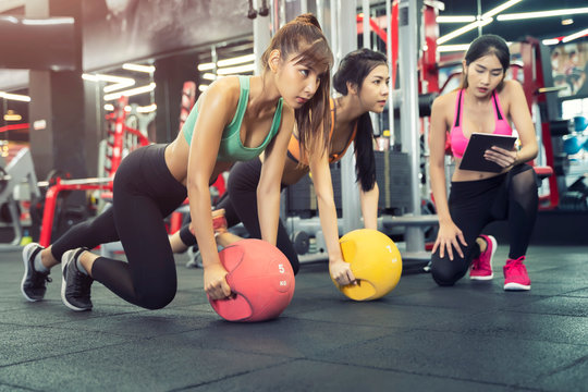 Sport women exercise together in gym with trainer. Fitness and healthy concept.