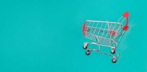 Close up of supermarket grocery push cart for shopping. Shopping trolley on light blue background....