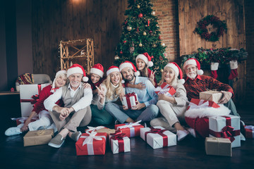 Portrait of nice charming cheerful big full family brother sister couples wearing cap hat headwear sitting on floor winter tradition showing v-sign in decorated loft industrial style interior house