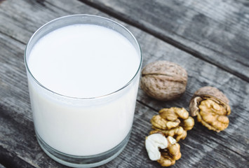 A glass of white milk and walnuts on an old wooden table. Vegan milk from walnuts. Eco food.