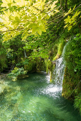 The pure fresh water of a small creek cascades into the azure coloured crystal clear water of a pond at the Plitvice Lakes National Park in Croatia