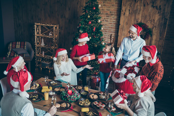 Top above high angle photo of big large family with small little kids mature sit around table x-mas meal man hold red sack back give gift box wish dream in house with christmas tree follow tradition