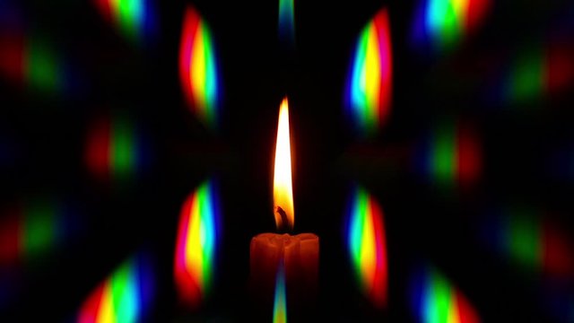 A candle flame in the wind fluctuates surrounded by rainbow diffraction patterns obtained by using a phase diffraction grating