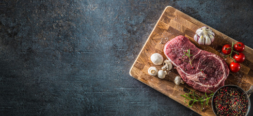 Obraz na płótnie Canvas Rib Eye steak salt pepper spices garlic and mushroom. Raw beef meat on butcher board - top of view