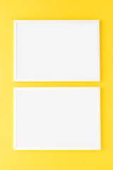 Two empty picture frames on yellow wall. Mockup with copyspace