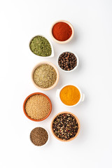 Various kinds of seasonings in bowls on white table. Top view