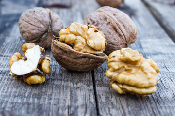 Peeled walnuts and walnut kernels lie on a rustic old wooden table.