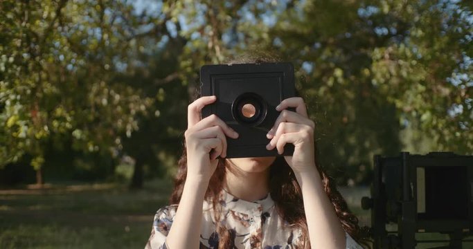 young woman setting up large format camera in nature