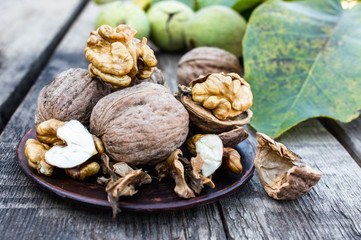 Walnuts and walnut kernels lie on a bowl on a rustic old wooden table. Walnut kernels.