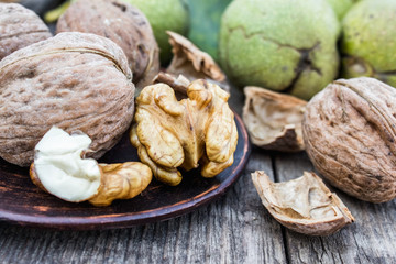 Walnuts and walnut kernels lie on a bowl on a rustic old wooden table. Walnut kernels.