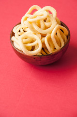 Chips onion rings in a clay Cup on a red background