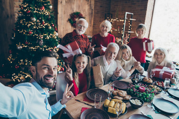 Self-portrait photo of nice cheerful big full family enjoying spending eve noel eating homemade brunch sharing gift tradition showing v-sign in modern industrial loft style interior decorated house