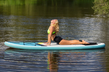 Blonde woman practicing yoga pose on SUP