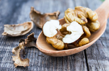Walnuts and walnut kernels lie in a spoon on a rustic old wooden table. Kernels of walnuts.