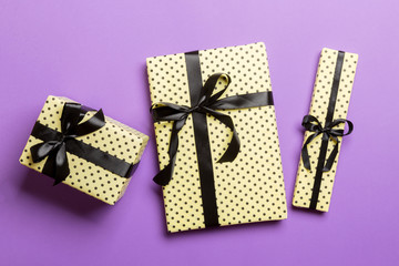 wrapped Christmas or other holiday handmade present in paper with Black ribbon on purple...