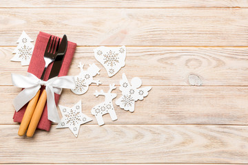 Top view of fork and knife on napkin on wooden background. Different christmas decorations and toys. New Year dinner concept with empty space for your design