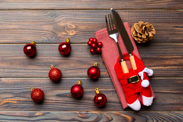 Top view of holiday set of fork and knife on wooden background. Close up of Christmas decorations and toys. New Year Eve concept