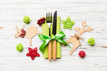 Top view of new year utensils on napkin with holiday decorations and reindeer on wooden background. Close up of christmas dinner concept