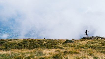  Hiker man take a rest on mountain peak. Man lay on summit, bellow autumn valley. Bright morning...