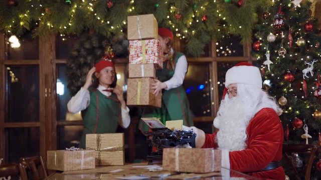 Santa Claus and elves with gift boxes. Santa Claus and elves in Christmas working