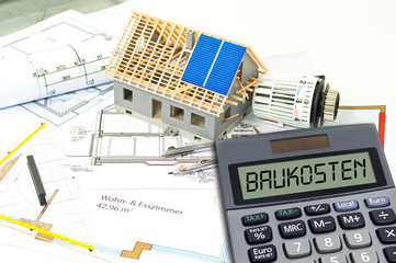 Fototapeta na wymiar Construction or building plan with bricks and calculator showing the german word for building costs - baukosten 