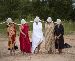 Naked women with closed heads with white material and wrapped in blankets