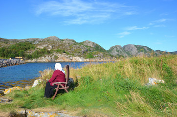 Old Woman Sitting on a Chair Next to the Shore in Norway
