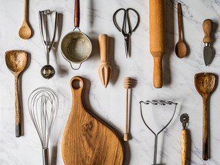flat lay various metal and wooden kitchen tools on marble background.