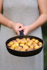 girl holds pan with whole baked potatoes.