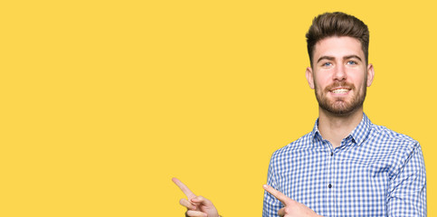 Young handsome bussines man smiling and looking at the camera pointing with two hands and fingers to the side.