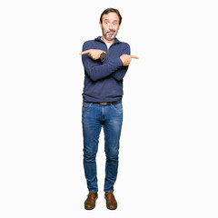 Middle age handsome man wearing a sweater Pointing to both sides with fingers, different direction disagree