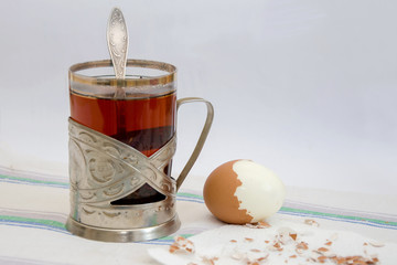 Still life, a glass of tea with a peeled egg on white, nostalgia for a tourist trip.