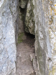 Rocky entrance to the cave, located in the densely growing Ural forest.