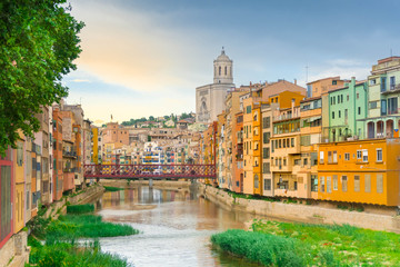 Girona colorful houses district, bridge, and Saint Mary Cathedral, buildings reflected in water in...