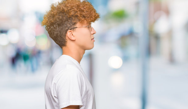 Young handsome man with afro hair wearing glasses looking to side, relax profile pose with natural face with confident smile.