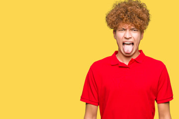 Fototapeta na wymiar Young handsome man with afro hair wearing red t-shirt sticking tongue out happy with funny expression. Emotion concept.