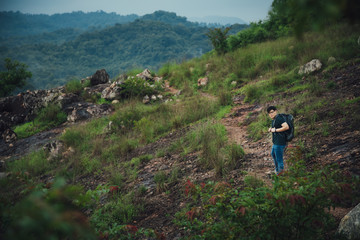 Young hiking man with backpack walking outdoor alone into the wild.
