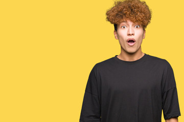 Young handsome man with afro hair wearing black t-shirt afraid and shocked with surprise expression, fear and excited face.