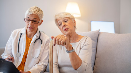 Health visitor and a senior woman during home visit. Female doctor talking to a senior woman. Doctor with senior woman in nursing home. Helpful doctor taking care of senior woman in nursing home