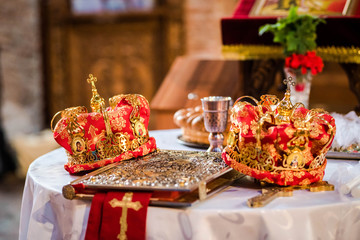 Fototapeta na wymiar Two crowns for a orthodox wedding ceremony , the bible and a glass of red wie