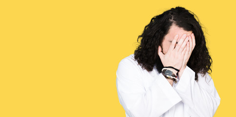 Man wearing Jesus Christ costume with sad expression covering face with hands while crying. Depression concept.