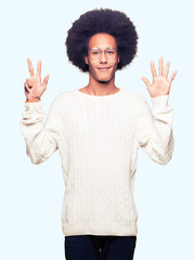 Young african american man with afro hair wearing glasses showing and pointing up with fingers number eight while smiling confident and happy.