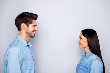 Side profile photo of cheerful charming beautiful couple of two people together setting eye contact speaking with each other wearing jeans denim isolated grey color background