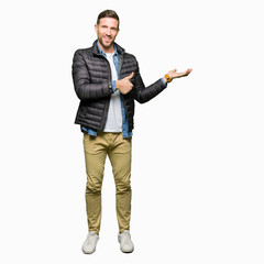 Handsome man wearing winter coat Showing palm hand and doing ok gesture with thumbs up, smiling happy and cheerful