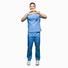 Handsome doctor man wearing medical uniform over isolated background smiling in love showing heart symbol and shape with hands. Romantic concept.