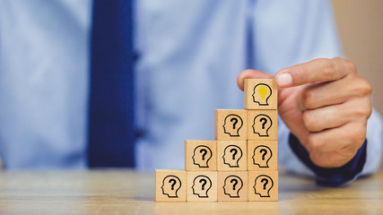 businesman hand arranging wood block with icon head human symbol and light bulb,concept creative...
