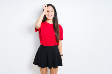 Obraz premium Beautiful brunette woman wearing red t-shirt and skirt over isolated background doing ok gesture with hand smiling, eye looking through fingers with happy face.